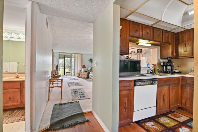 kitchen featuring dishwasher, light hardwood / wood-style floors, a textured ceiling, and sink