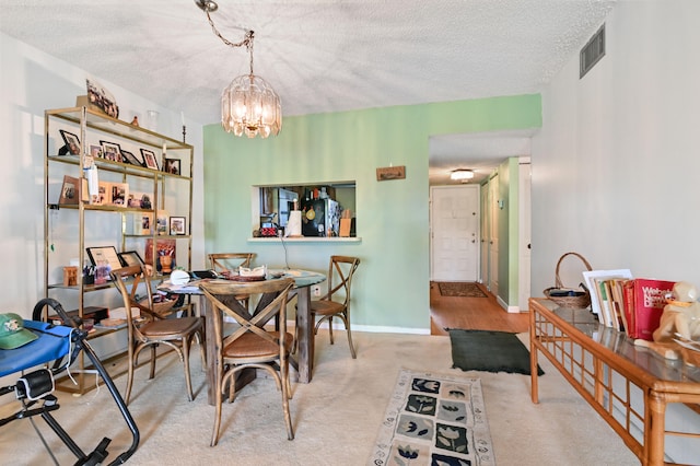 carpeted dining space featuring a chandelier and a textured ceiling