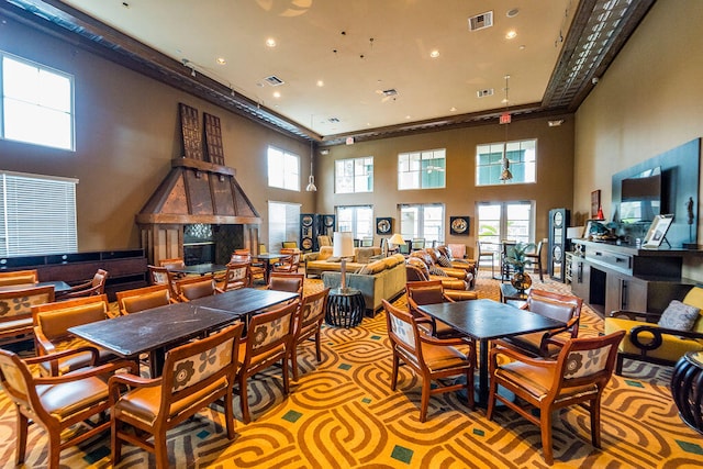 dining area with a towering ceiling and a fireplace