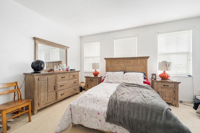 bedroom featuring light colored carpet and multiple windows