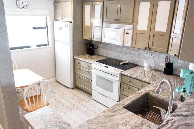 kitchen with white appliances, light stone countertops, backsplash, and sink