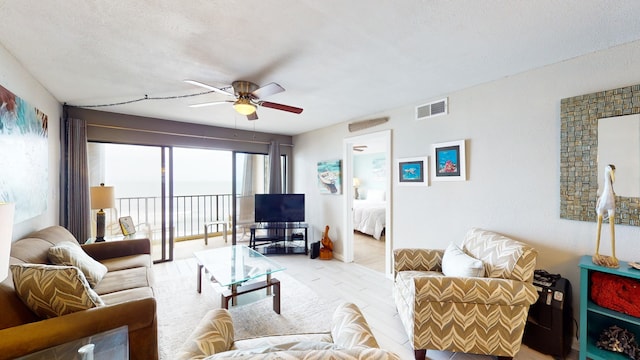 living room with a textured ceiling and ceiling fan