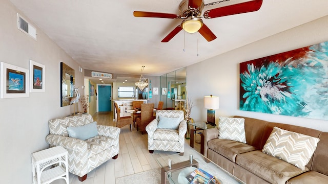 living room with ceiling fan with notable chandelier and light wood-type flooring