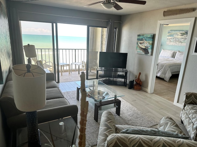 living room with a water view, light hardwood / wood-style floors, and ceiling fan