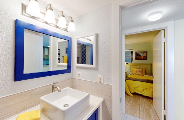 bathroom with tile walls, vanity, a textured ceiling, and crown molding