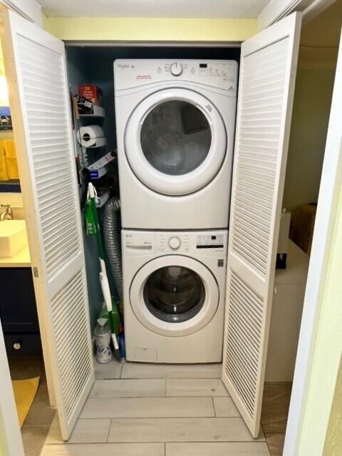 clothes washing area with stacked washer and dryer and sink