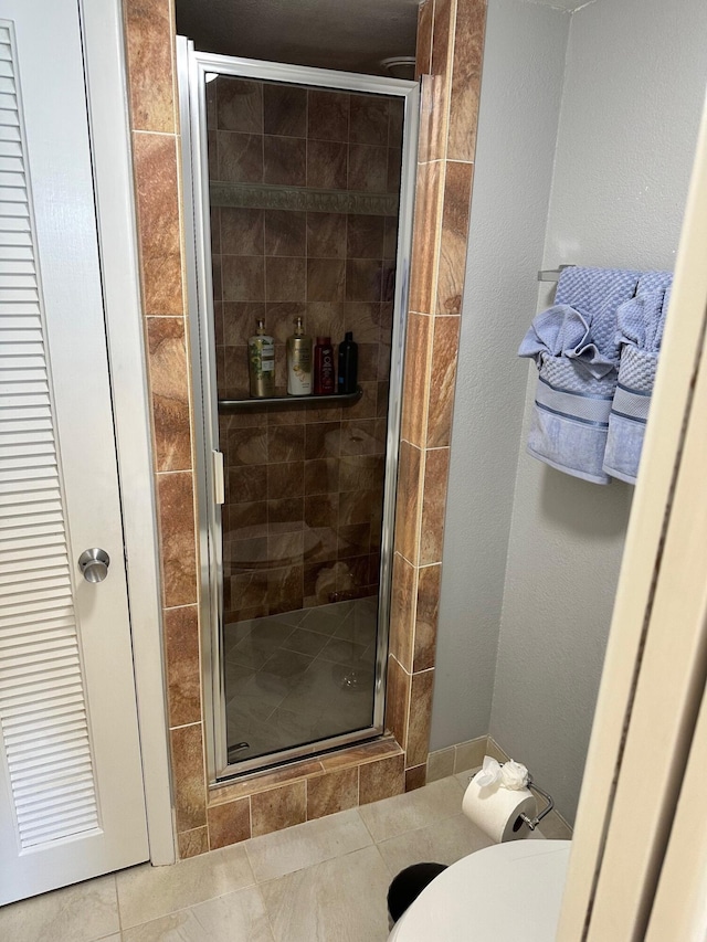 bathroom with an enclosed shower, tile floors, and toilet