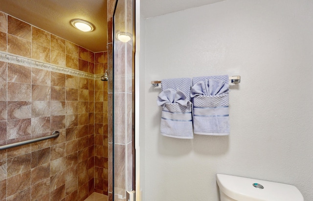 bathroom featuring toilet and a shower with shower door