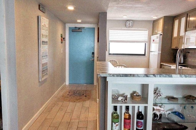 kitchen with white appliances, a textured ceiling, sink, and light wood-type flooring