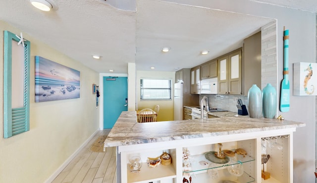 kitchen featuring white appliances, tasteful backsplash, a textured ceiling, and light wood-type flooring