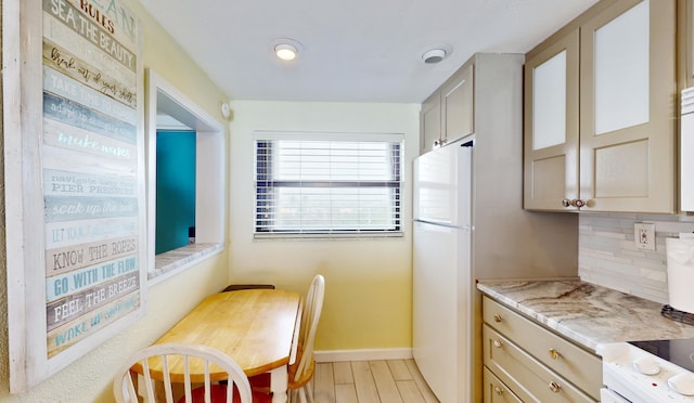 kitchen featuring range, white fridge, light hardwood / wood-style floors, light stone counters, and tasteful backsplash