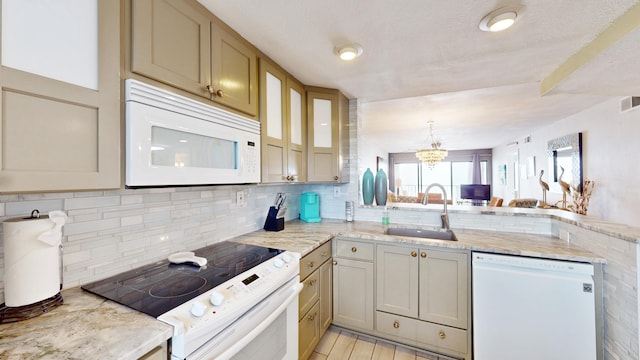 kitchen with white appliances, a notable chandelier, light stone counters, and sink