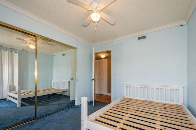 carpeted bedroom with a closet, a textured ceiling, ceiling fan, and ornamental molding