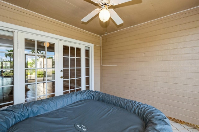 tiled bedroom with ceiling fan, wood walls, and french doors