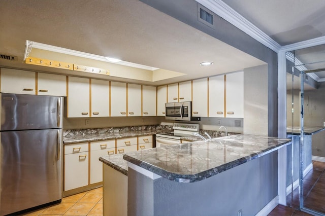 kitchen with dark stone countertops, white cabinets, kitchen peninsula, and stainless steel appliances