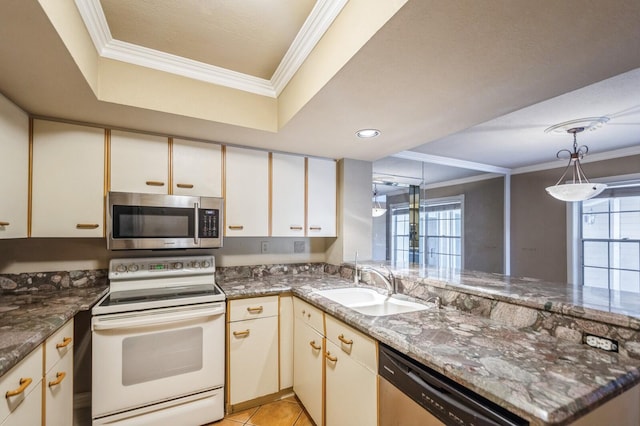 kitchen with kitchen peninsula, sink, dark stone counters, appliances with stainless steel finishes, and a tray ceiling