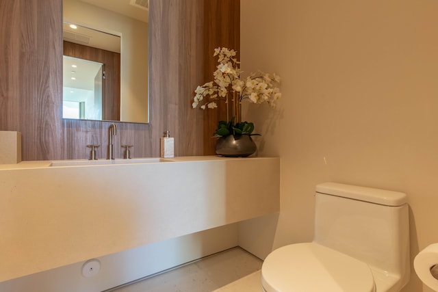 bathroom featuring wooden walls, sink, and toilet