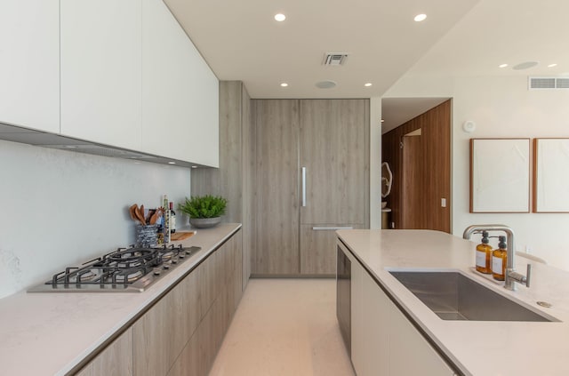 kitchen featuring white cabinets, stainless steel gas stovetop, and sink