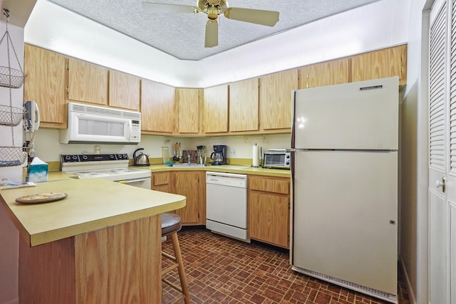 kitchen featuring a breakfast bar, white appliances, sink, ceiling fan, and kitchen peninsula