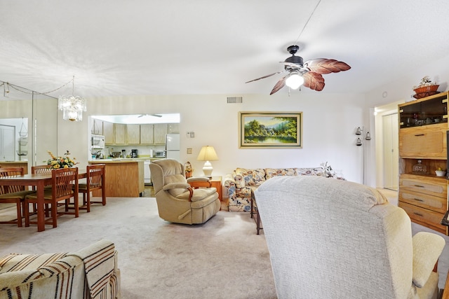 carpeted living room featuring ceiling fan with notable chandelier