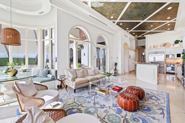 living room featuring a towering ceiling, ornamental molding, coffered ceiling, light tile flooring, and a tray ceiling