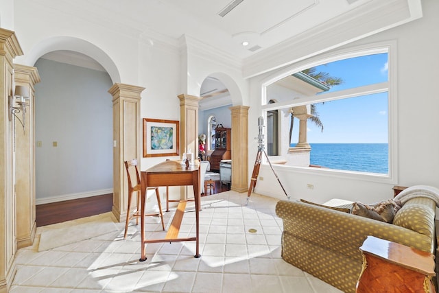 interior space with a water view, ornamental molding, decorative columns, and light wood-type flooring