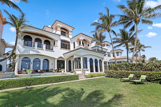 view of front of property featuring a balcony, a front lawn, and a patio area