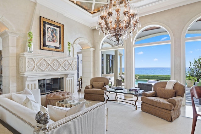 living room featuring coffered ceiling, decorative columns, an inviting chandelier, a water view, and crown molding