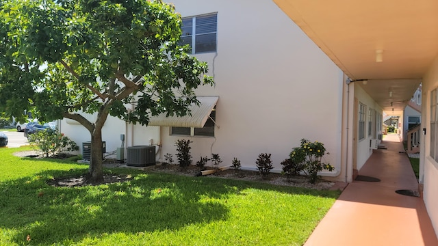 view of property exterior with a lawn and central AC