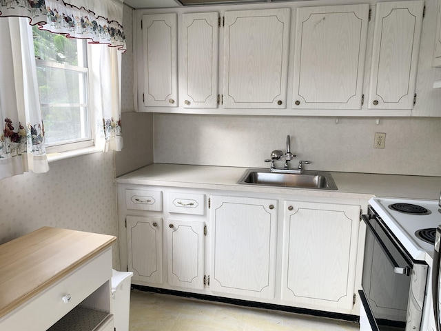 kitchen featuring white cabinetry, range with electric cooktop, and sink