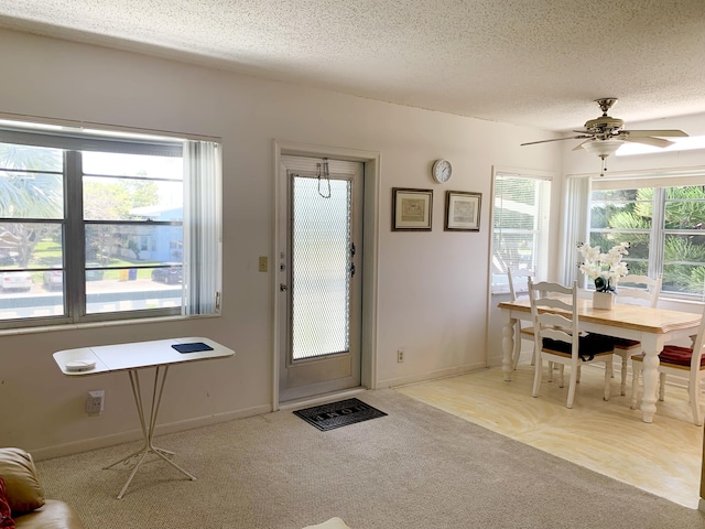 entrance foyer with a textured ceiling, ceiling fan, and light carpet