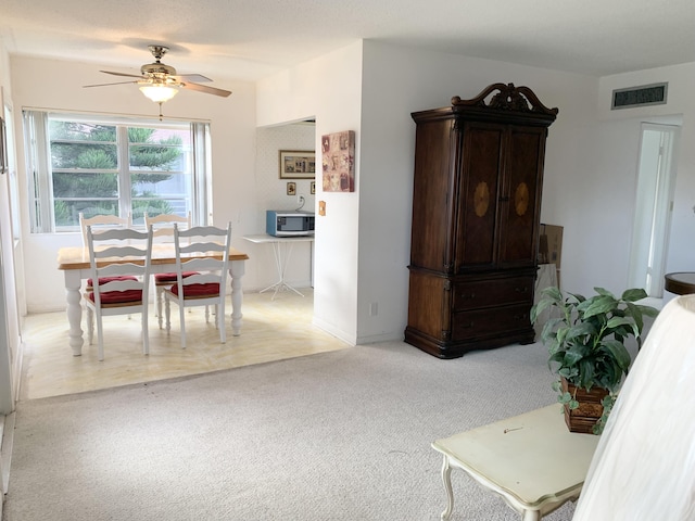 dining space featuring ceiling fan and light colored carpet