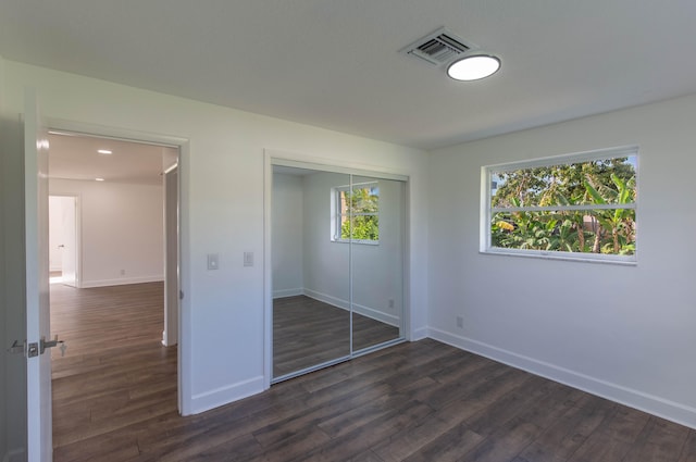 unfurnished bedroom with dark hardwood / wood-style flooring and a closet