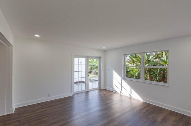 empty room featuring french doors, a textured ceiling, and dark wood-type flooring