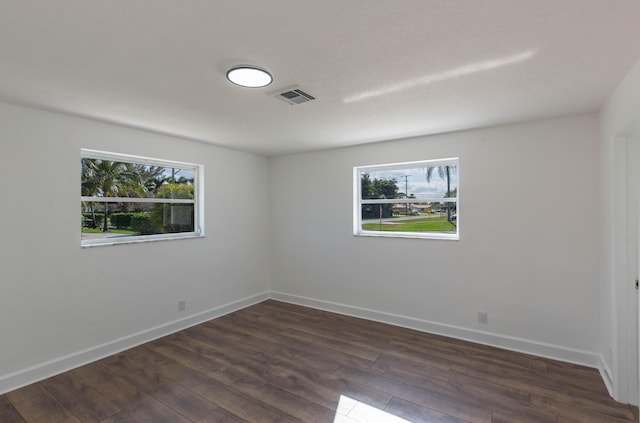 spare room featuring dark wood-type flooring and a healthy amount of sunlight