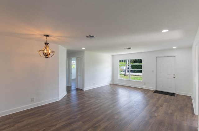 empty room featuring a notable chandelier and dark wood-type flooring