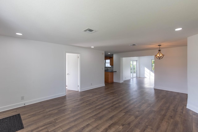 unfurnished living room with dark hardwood / wood-style floors and an inviting chandelier