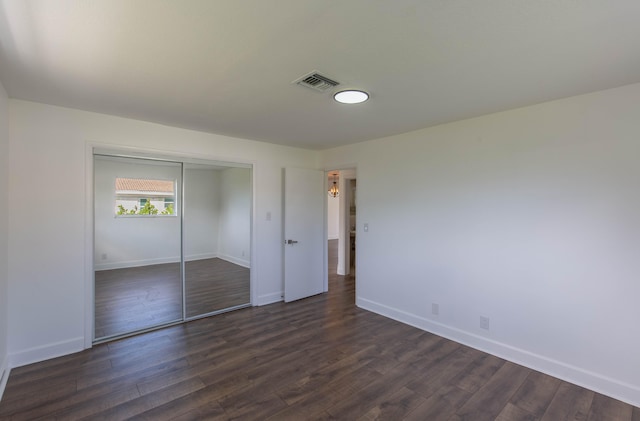 unfurnished bedroom with a closet and dark wood-type flooring