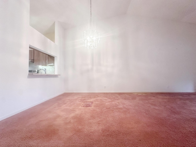 unfurnished room featuring high vaulted ceiling, an inviting chandelier, and carpet flooring