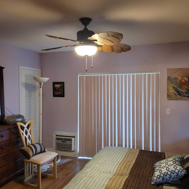 bedroom with a wall mounted AC, ceiling fan, and dark wood-type flooring