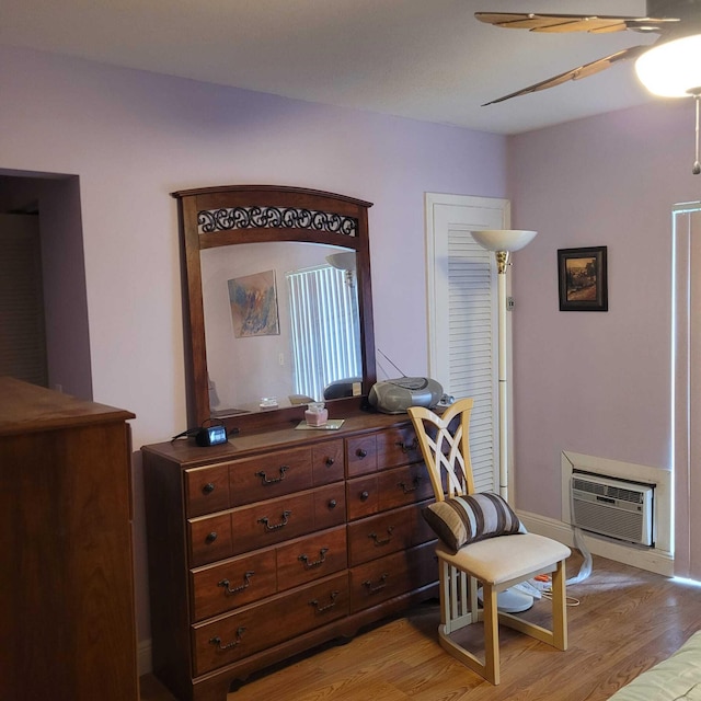 living area featuring a wall mounted air conditioner, light hardwood / wood-style floors, and ceiling fan