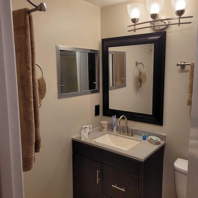 bathroom with toilet, vanity, and a notable chandelier