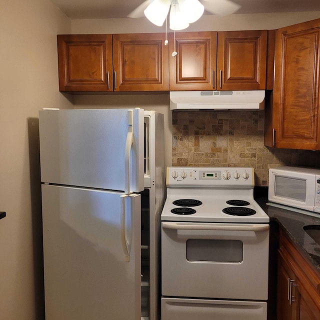 kitchen featuring backsplash, white appliances, ceiling fan, and dark stone counters