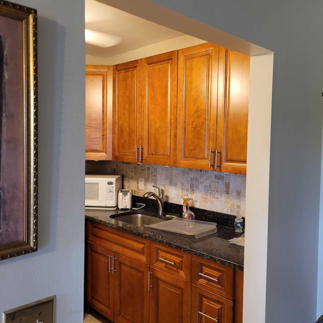 kitchen featuring dark stone counters, tasteful backsplash, and sink