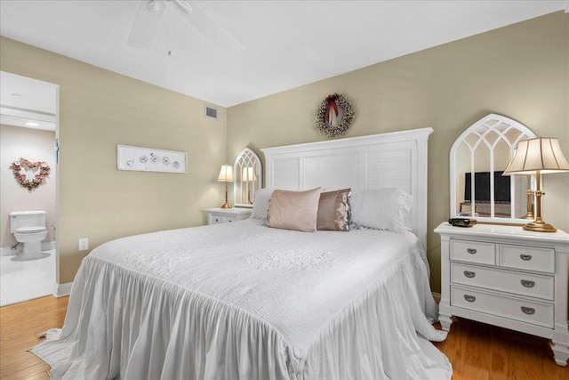 bedroom featuring ceiling fan, light hardwood / wood-style flooring, and connected bathroom