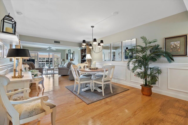 dining area with light hardwood / wood-style floors and ceiling fan with notable chandelier