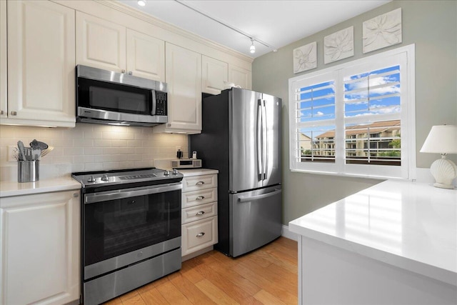 kitchen with backsplash, track lighting, light hardwood / wood-style flooring, stainless steel appliances, and white cabinets