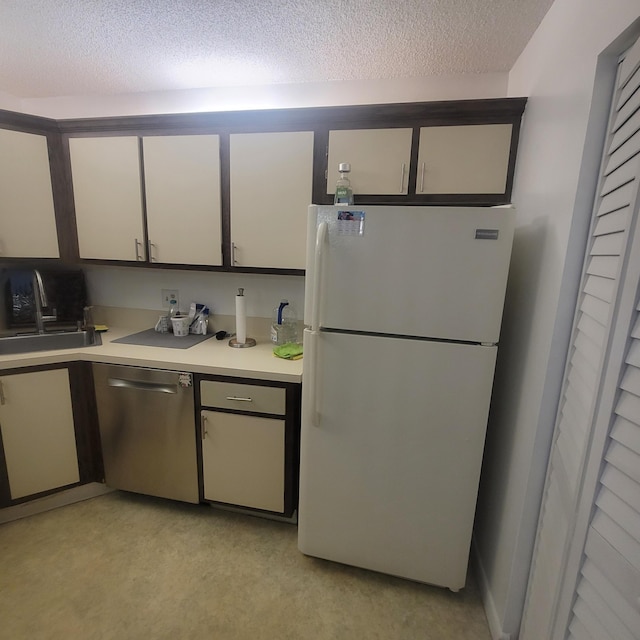 kitchen with white fridge, sink, a textured ceiling, stainless steel dishwasher, and light colored carpet