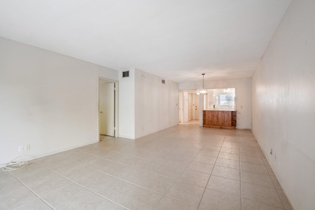 spare room with an inviting chandelier and light tile floors