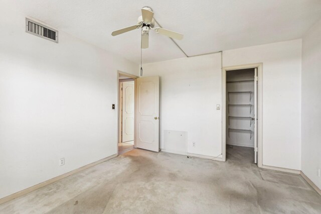 unfurnished bedroom featuring a spacious closet, a closet, ceiling fan, and light colored carpet